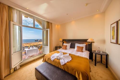 a bedroom with a large bed and a large window at Grand Hotel Amrâth Kurhaus The Hague Scheveningen in Scheveningen