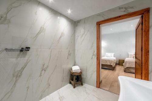 a bathroom with white marble walls and a mirror at Leyla Luxury Villa in Pláka