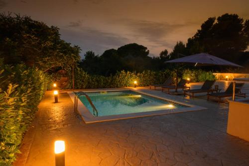 uma piscina à noite com velas e guarda-sóis em Villa Vinko em Trogir