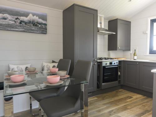 a kitchen with a glass table with chairs and appliances at Oakwood 2 Pinewood Retreat in Lyme Regis