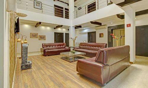 a large living room with leather couches and a table at Blue Moon Residency Hotel & Restaurant in Gurgaon
