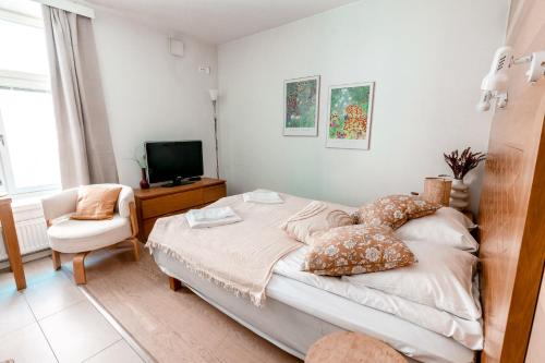 a bedroom with a bed and a chair and a television at 2ndhomes Compact Studio by the Esplanade Park in Helsinki