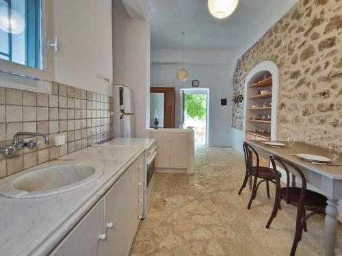 a kitchen with a sink and a table and chairs at Στούντιο σε πέτρινο σπίτι, κοντά σε παραλία in Kyparissia