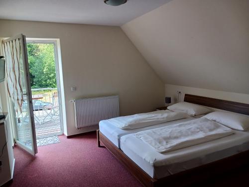 ein Schlafzimmer mit einem großen Bett und einer Glasschiebetür in der Unterkunft Hotel Forsthaus Glüsing in Schnakenbek