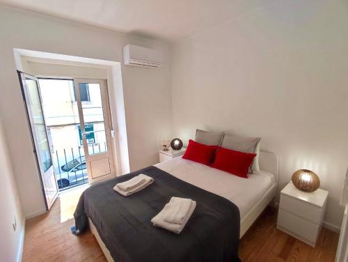 a white bedroom with a large bed with red pillows at Red Passion Apartment in Lisbon