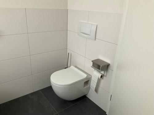 a bathroom with a toilet in a white tiled wall at Apartment Auszeit in Bad Neustadt an der Saale