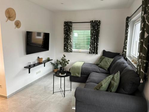 ein Wohnzimmer mit Sofa und Fernseher in der Unterkunft Ferienvilla 10 Minuten vom Strand in Dirkshorn