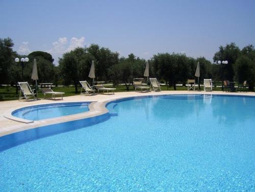 a large blue swimming pool with chairs and umbrellas at Agriturismo Masseria Baronali in Borgagne