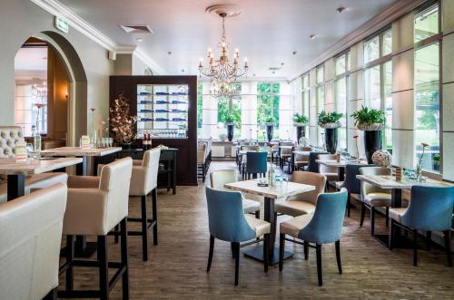 a restaurant with tables and chairs and a chandelier at Hampshire Hotel - Avenarius in Ruurlo