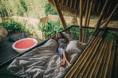 a woman laying on a bed in a hammock at Balikayanas - Ellena House in Karangasem