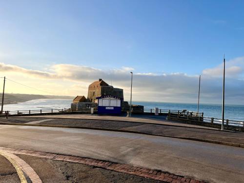 an empty road next to the ocean with a building at La Maison - Ambleteuse - Vue sur Mer et Jardin in Ambleteuse