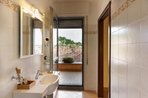 baño con lavabo, espejo y ventana en Hotel Il Grappolo D'Oro, en Monforte dʼAlba