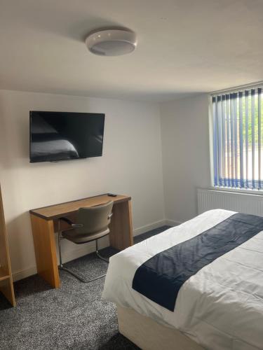 a bedroom with a bed and a desk and a television at City apartments college street in Hull