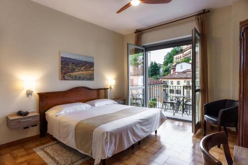 a bedroom with a large bed and a large window at Hotel Il Grappolo D'Oro in Monforte dʼAlba