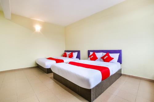 2 camas en una habitación con almohadas rojas y azules en Happy Inn Hotel, en Banting