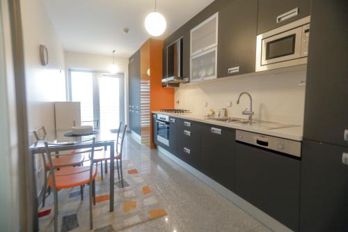 a kitchen with a table and chairs and a sink at Afurada premium apartment by Porto City Hosts in Vila Nova de Gaia