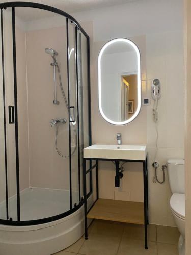 La salle de bains est pourvue d'une douche, d'un lavabo et d'un miroir. dans l'établissement Aparthotel Maria, à Cracovie