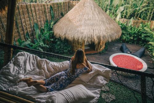 a woman laying on a blanket in a cage at Balikayanas - Ellena House in Karangasem