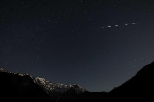 a jet trail in the night sky over a mountain at Nakaodaira in Takayama