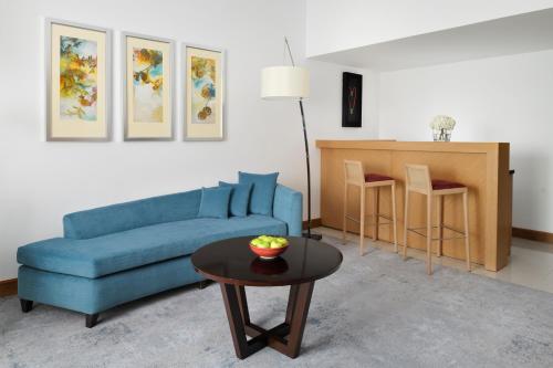 a living room with a blue couch and a table at Mövenpick Hotel Jumeirah Beach in Dubai