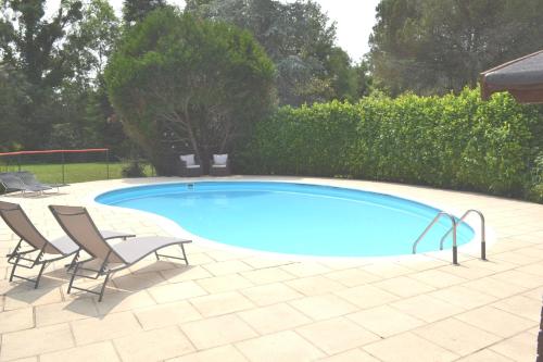 a swimming pool with two lawn chairs and a table at Les Bruyeres Gite in Montbron
