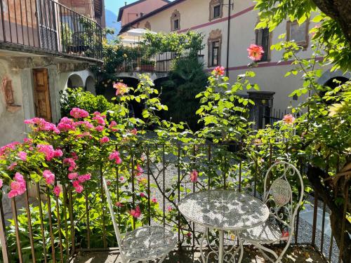 a table and chairs in a garden with pink flowers at Piano nobile al Roseto del Drago in San Bernardo