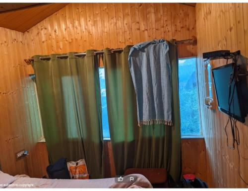 a bedroom with green curtains in a wooden wall at Grand Mala Resorts, Pahalgam in Pahalgām