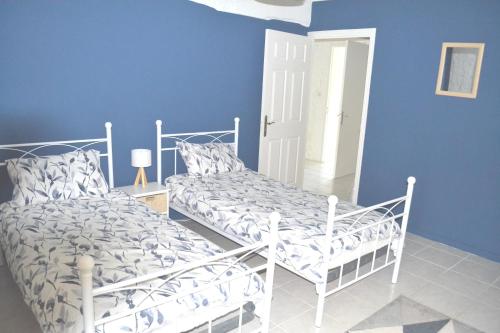Les Bruyeres Gite في Montbron: غرفة نوم بسريرين وجدار ازرق