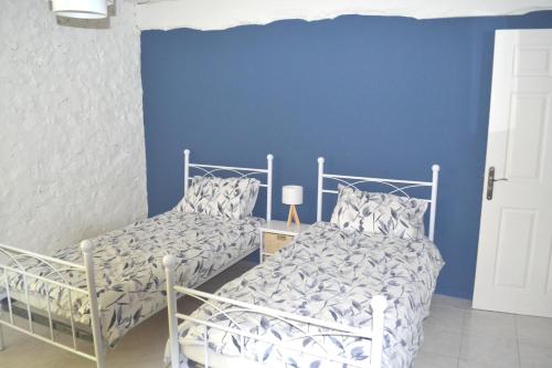 a bedroom with two beds and a blue wall at Les Bruyeres Gite in Montbron