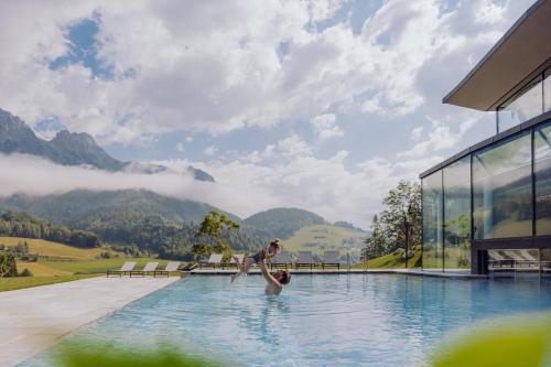 a man and a boy playing in a swimming pool at Naturresort PURADIES in Leogang