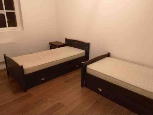 two beds in a room with wooden floors at Logement 10 min des sanctuaires in Paray-le-Monial