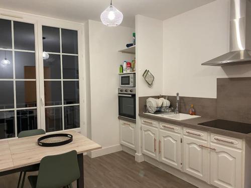 a kitchen with white cabinets and a table with chairs at Logement 10 min des sanctuaires in Paray-le-Monial