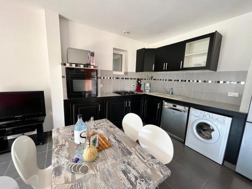 a kitchen with a table and white chairs in it at residence Catalani in Zonza