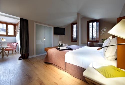 a bedroom with a large white bed and a living room at Exe Casa de Los Linajes in Segovia