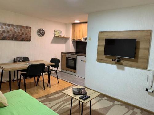 a living room with a table and a kitchen with a tv at Apartman K&K in Pirot