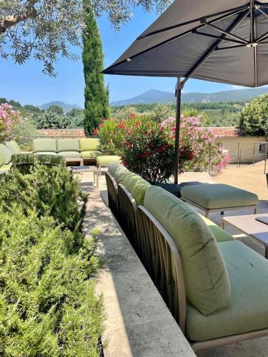 a row of green couches and an umbrella at Clos Saint-Michel Resort & Spa in Malaucène