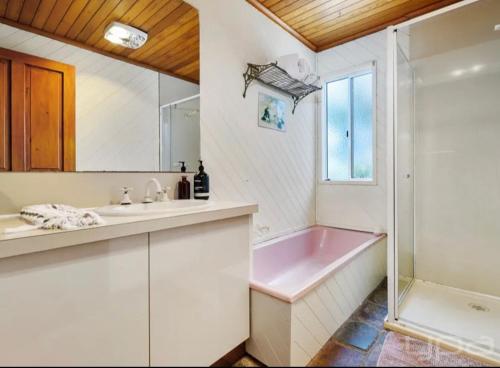 a bathroom with a pink tub and a sink at 4 bedrooms Relaxing farmhouse getaway in Glenmore 