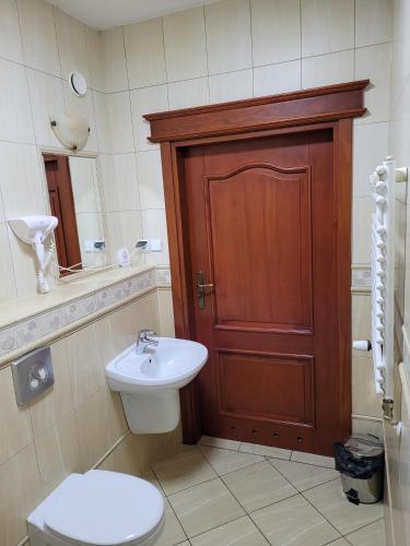 a bathroom with a toilet and a sink and a wooden door at Hotel Leliwa in Leśna