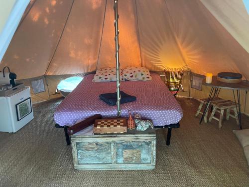 une tente avec un lit et une table. dans l'établissement CYBÈLE, à Bernac