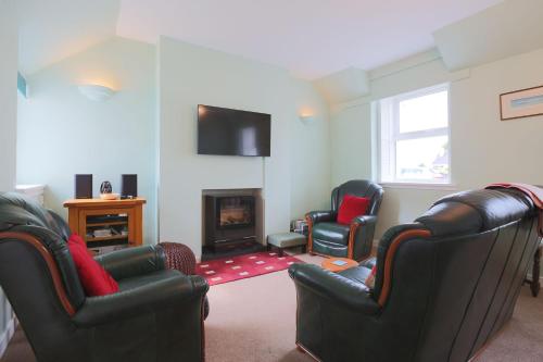 a living room with three chairs and a fireplace at Silver Lodge in Creetown