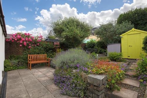 a garden with a bench and flowers and a yellowshed at Silver Lodge in Creetown