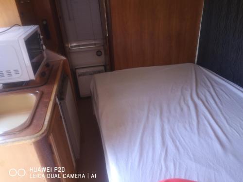 - une petite chambre avec un lit et un four micro-ondes dans l'établissement chambre en camping car, à Saint-Jean-de-Monts