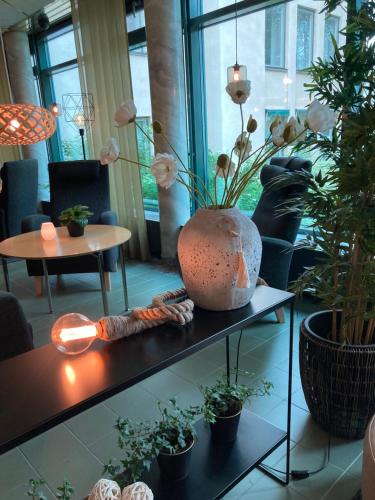 un jarrón sentado en una mesa en una habitación con plantas en Hotell Björken, en Umeå