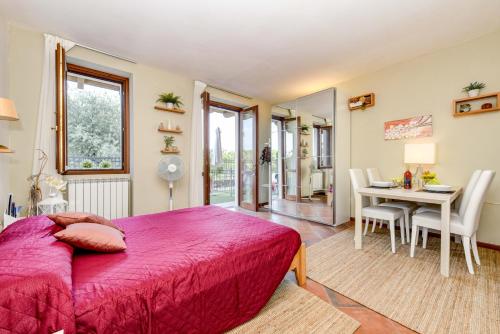 Schlafzimmer mit einem roten Bett, einem Tisch und Stühlen in der Unterkunft ACE Albatros GHH in Toscolano-Maderno