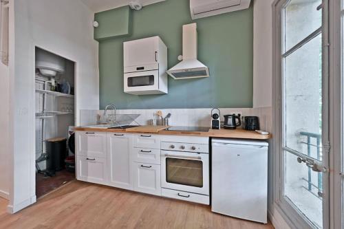 una cucina con mobili bianchi e un forno a piano cottura di Au coeur des Platanes - Parking Gratuit Sous-Terrain - CLiM - Balcon ad Avignone