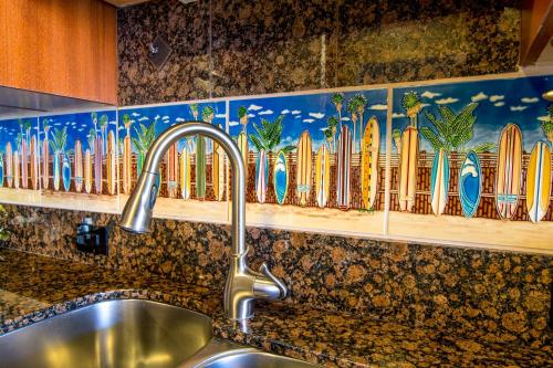 a kitchen counter with a sink and surfboards on a wall at Kaanapali Shores 448 in Kaanapali