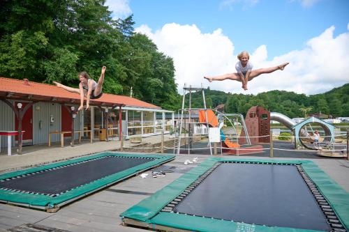 two girls jumping into a pool on a trampoline at Randbøldal Camping & Cabins in Randbøl