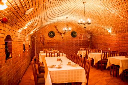 a restaurant with white tables and chairs and a brick wall at Nosztalgia Vendégház in Zalaegerszeg