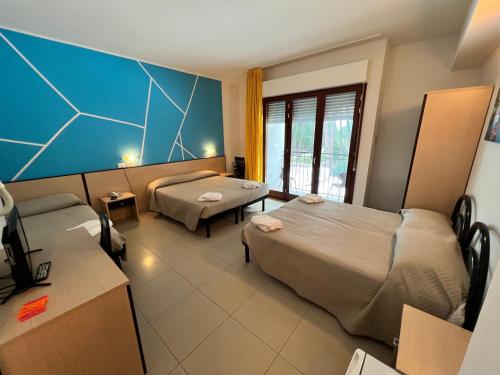 une chambre d'hôtel avec deux lits et un canapé dans l'établissement Club Vacanze In, à Cervia