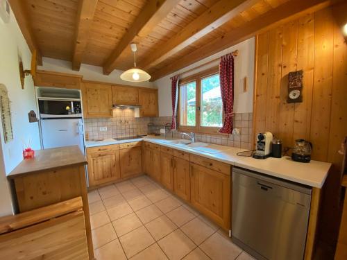 Il comprend une grande cuisine avec des placards en bois et un réfrigérateur. dans l'établissement Chalet calme et spacieux, proche village, navette ski, jardin, animaux acceptés, parking privé - FR-1-624-66, à Samoëns
